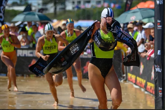 Surf lifesaving competitors sprinting up the beach to the finish line